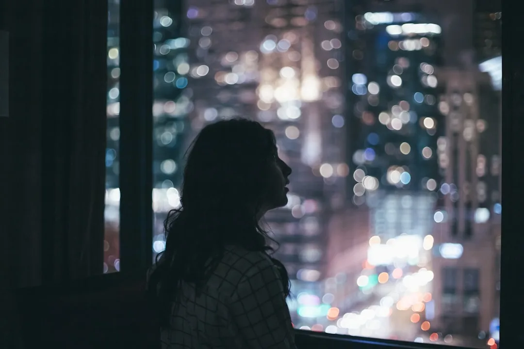 Thoughtful adult looking through a window toward the city