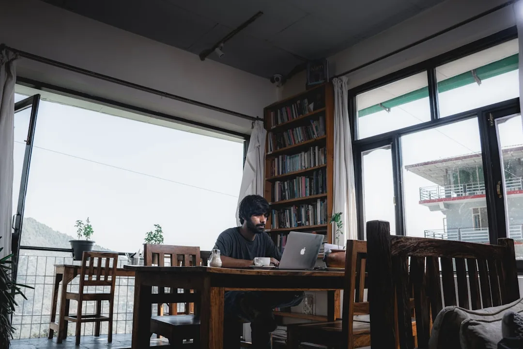 University student working on a laptop beside a bright window